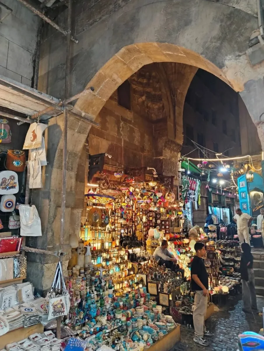 A lantern-lit market stall under an old stone arch on Al-Muizz Street