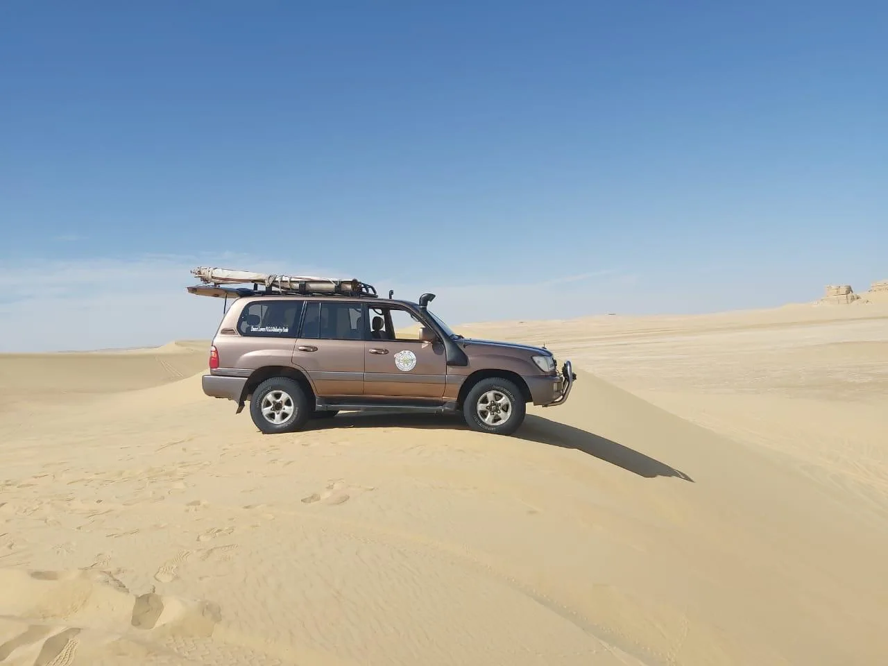 A 4x4 on the crest of a sand dune