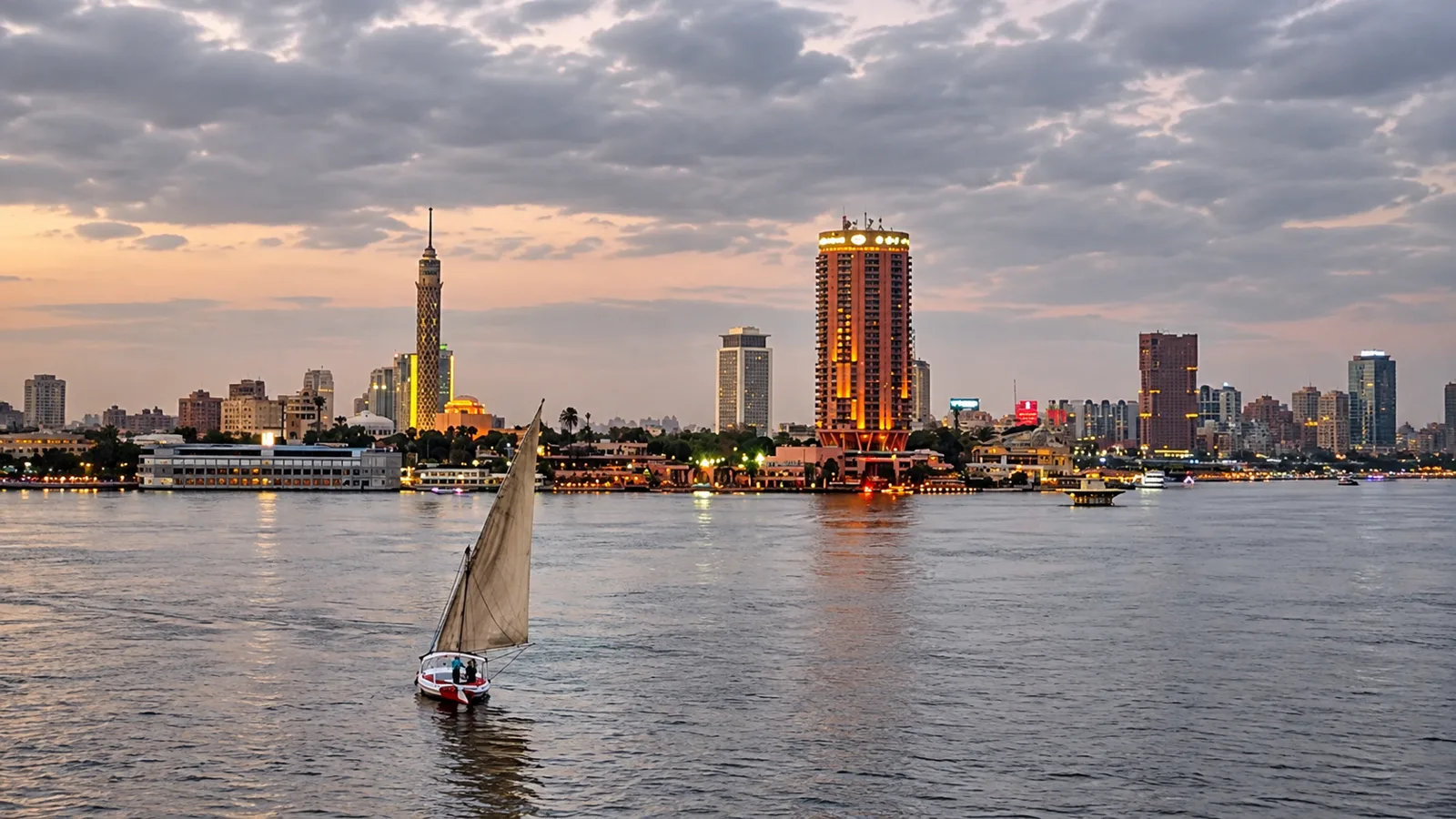 A felucca on the Nile at twilight with the Cairo skyline behind