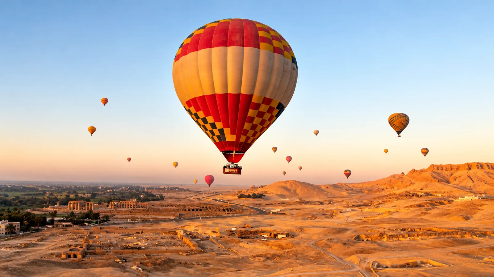 Hot air balloons rising at sunrise over ancient desert ruins